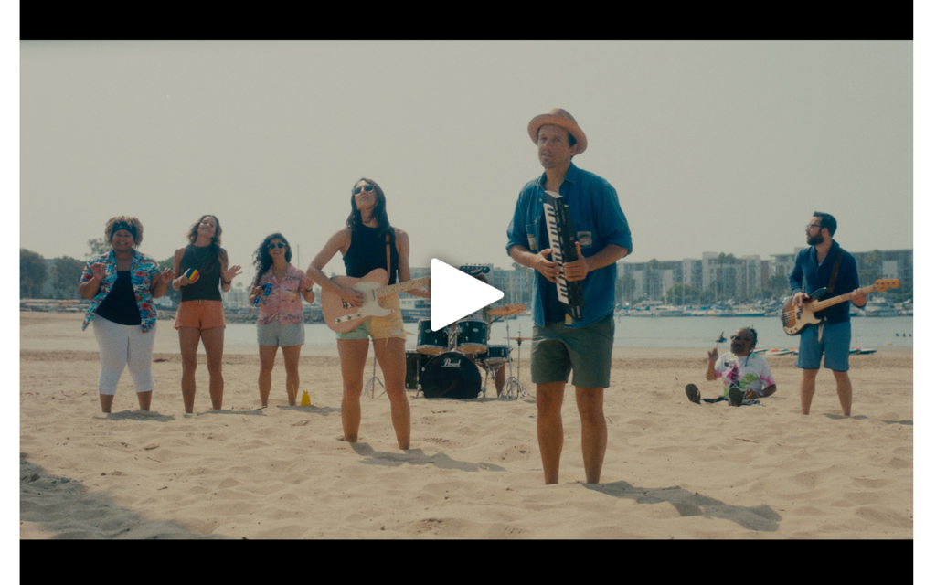 Jason Mraz and band on the beach with feet stuck in the sand